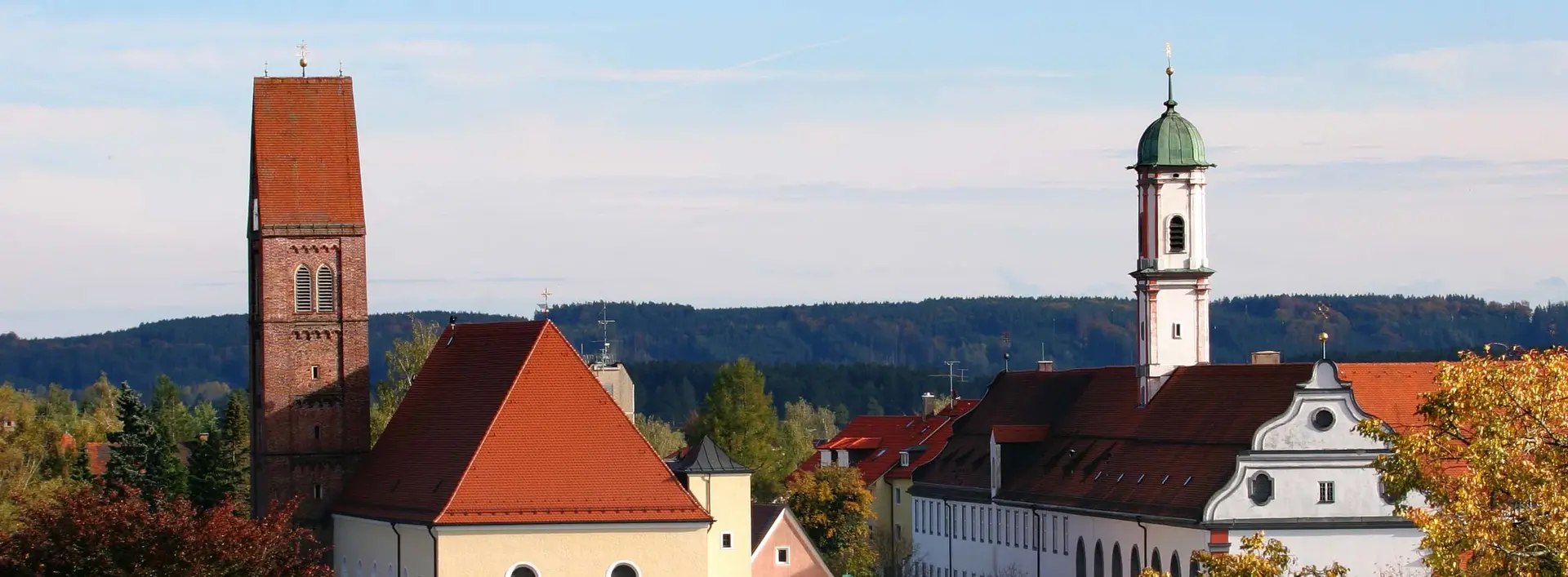 Panoramabild von Bad Wörishofen, mit Kloster und Kirche im Blick, Bäume und blauer Himmel